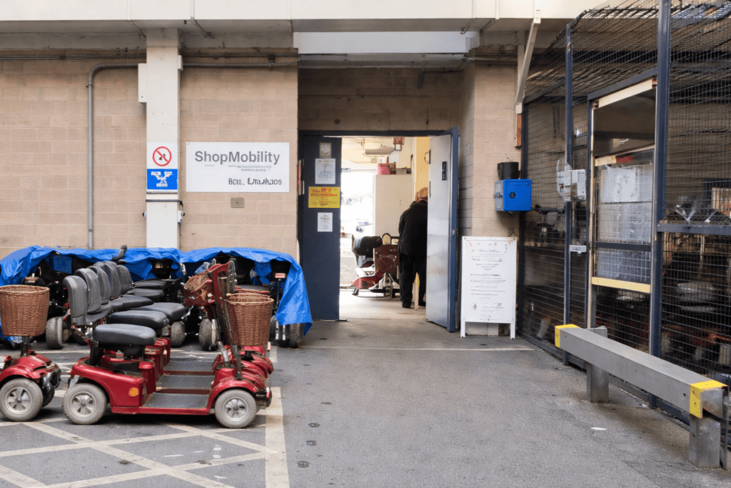 ShopMobility Worcester entrance inside Crowngate Car Park, with mobility scooters parked outside and step-free access into the office and accessible toilet.